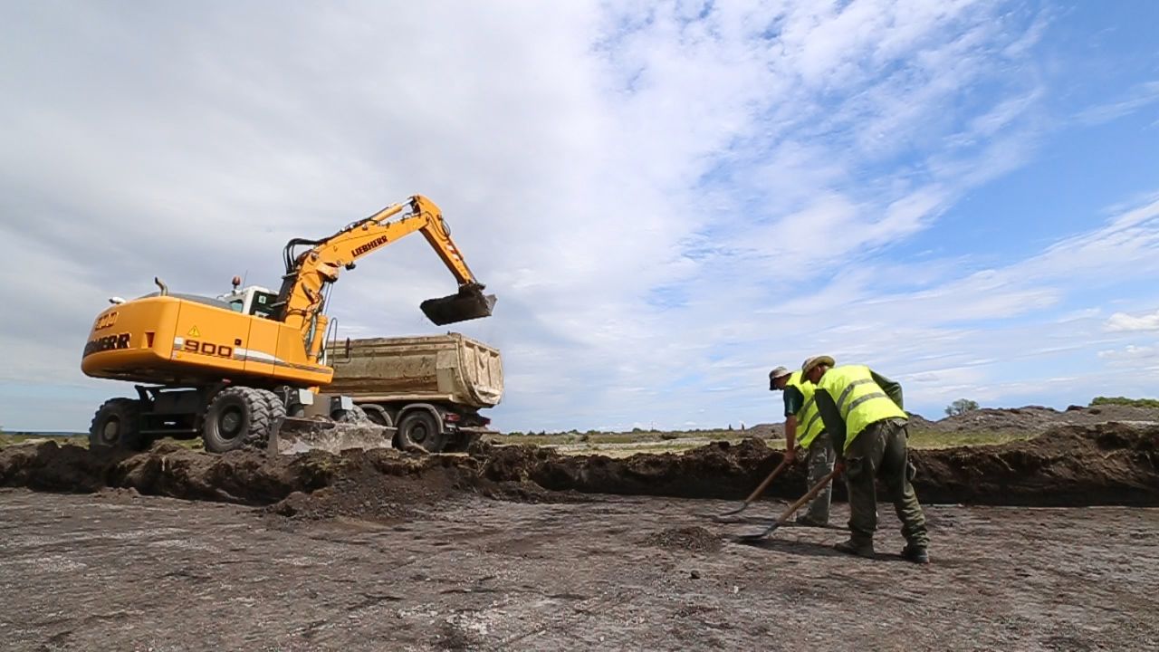 A humusztakaró eltávolítása gépi földmunkával régész felügyelete mellett zajlik. A gép nyomában haladva úgynevezett nyeséssel képeznek tükörfelületet, hogy a régészeti objektumok foltjai kirajzolódjanak a felszínen.